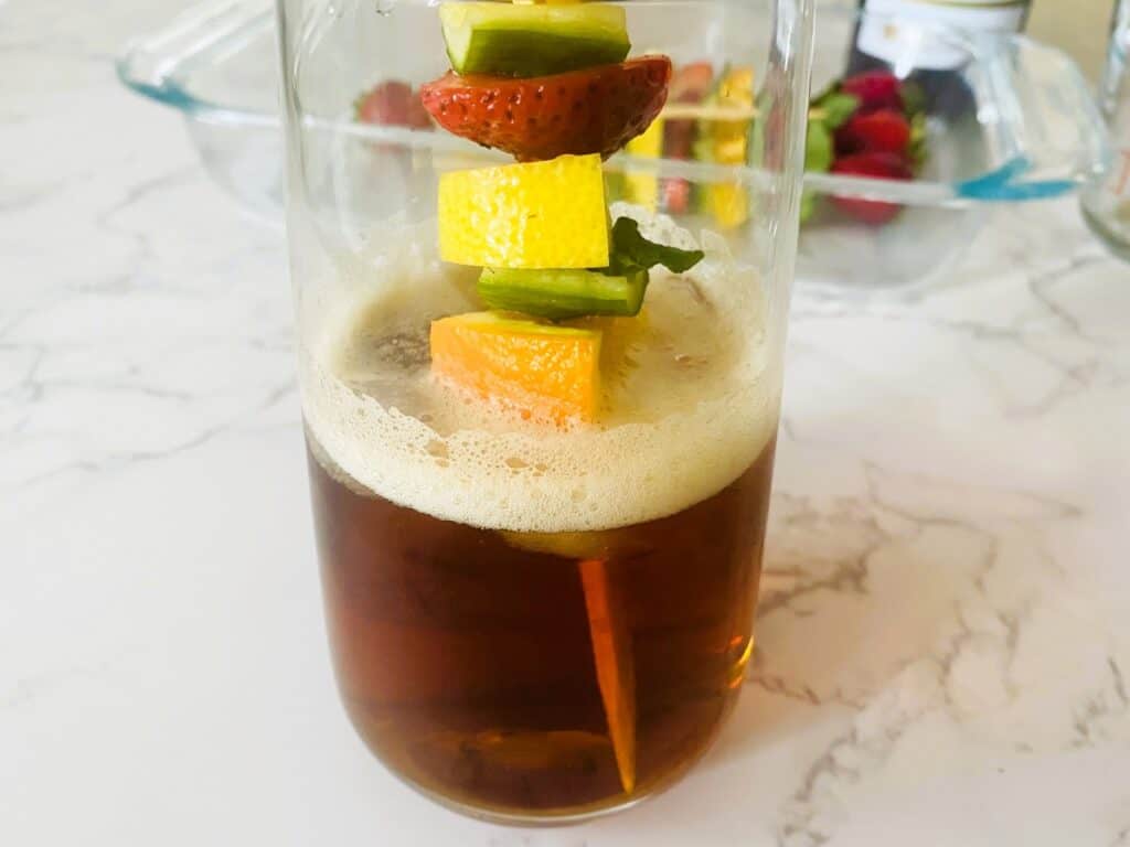 Pimms half and half with fruit skewer in a glass