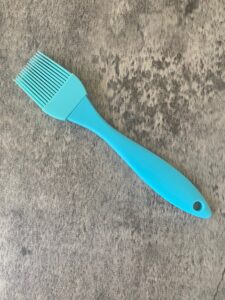 A blue pastry brush sits on a concrete bench