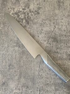 A kitchen knife sitting on a marble bench