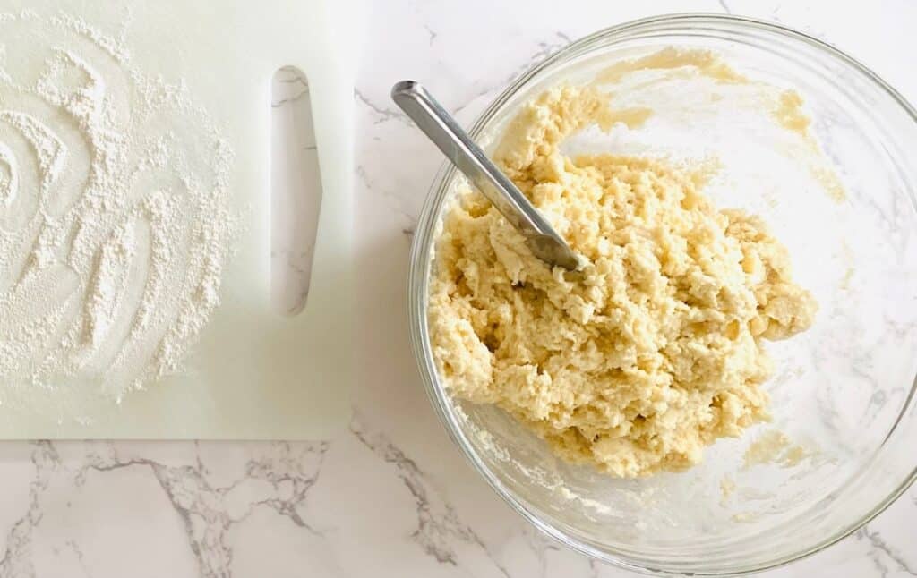 A bowl with scone dough next to a floured chopping board