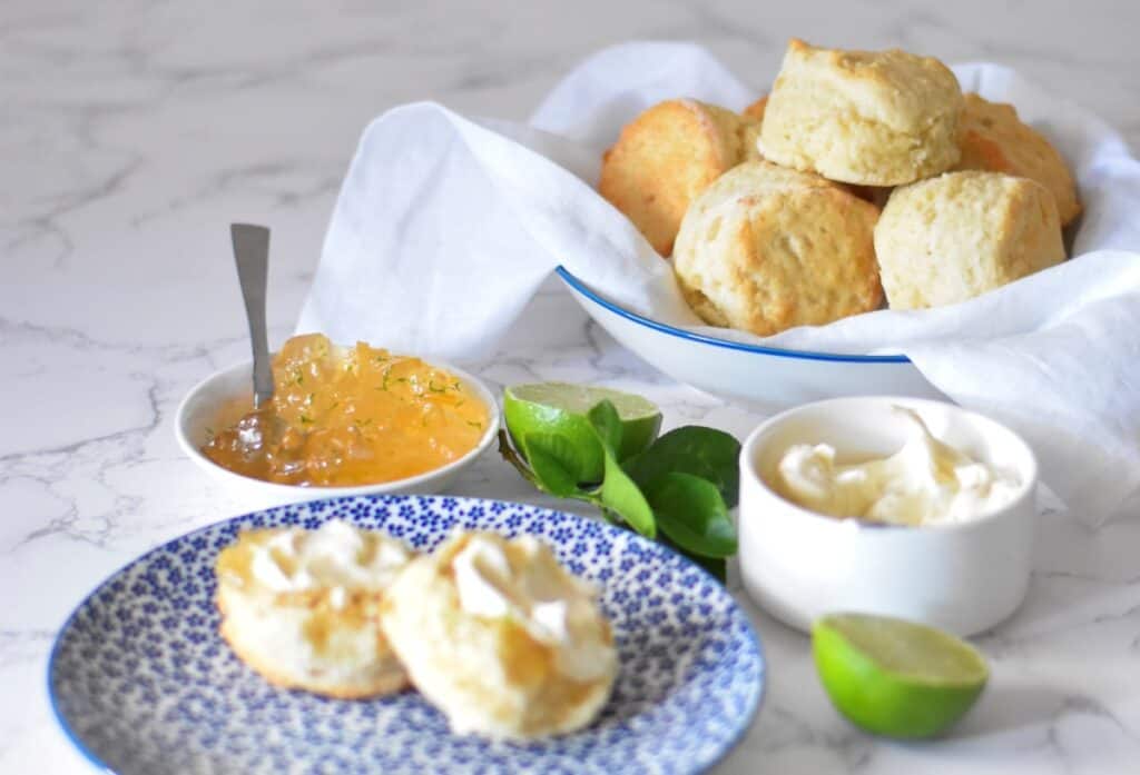 Ginger scones recipe. Fluffy scones sit on a plate with marmalade and fresh cream