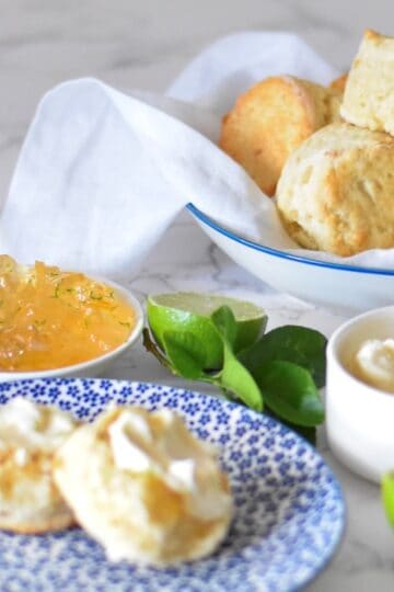 Ginger scones recipe. Fluffy scones sit on a plate with marmalade and fresh cream