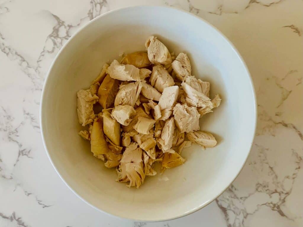 A bowl on a marble bench with chopped chicken