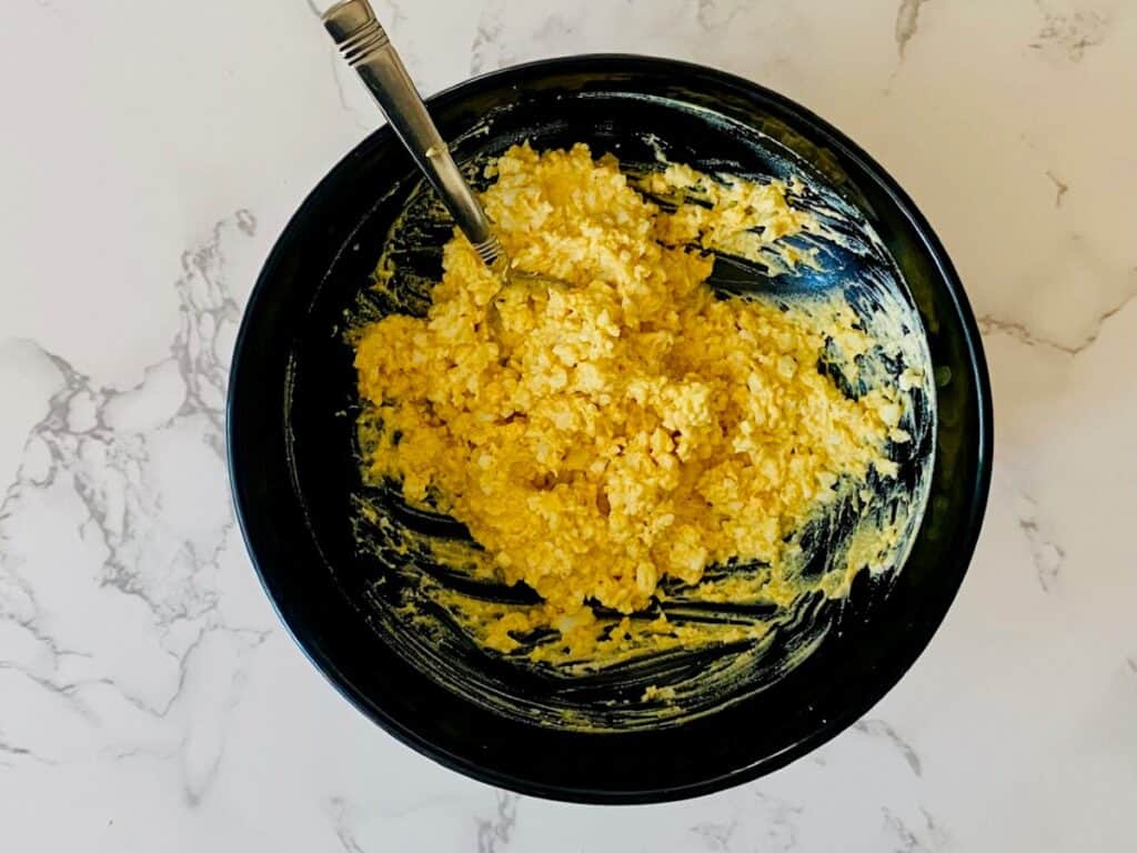 A black bowl with curried egg mixture and a spoon