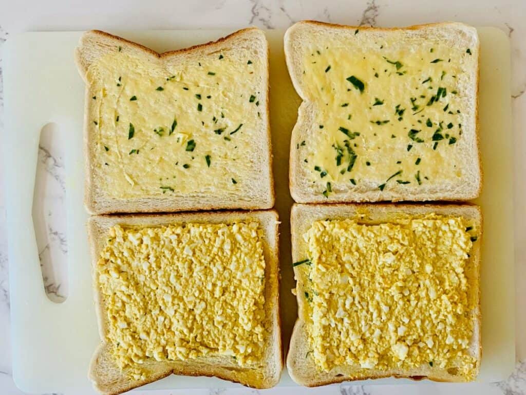 Four slices of bread, two with parsley butter and two with curried egg mixture