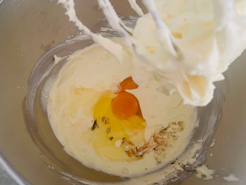 Filling ingrdients in a stand mixer for raspberry white chocolate cheesecake
