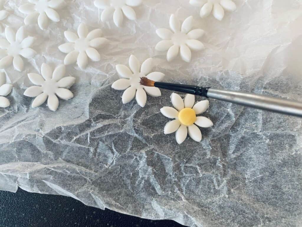 Fondant daisies having their centres applied