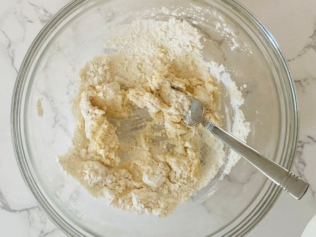 Flour and a little milk sit in a bowl with a fork