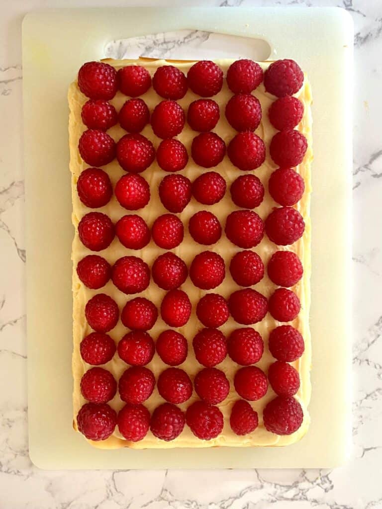 Raspberry white chocolate cheesecake slice sits on a cutting board