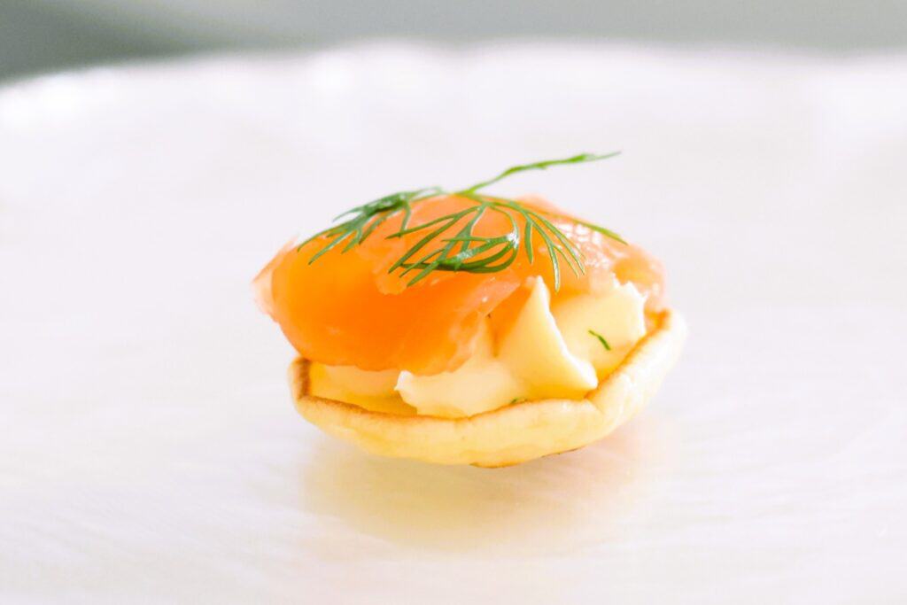 Single smoked salmon pikelet sits on a fancy stand