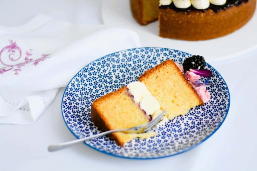 Lemon & blackberry sandwich cake slice on a blue and white plate