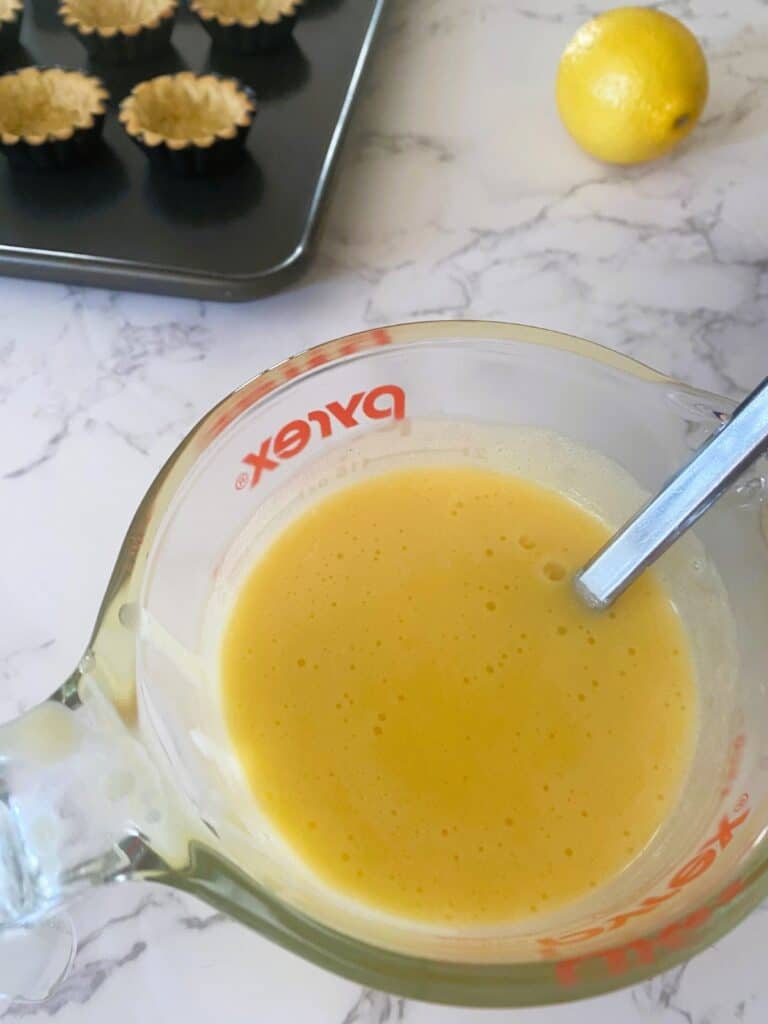 Lemon filling in a jug for Lemon Tartlets with Pistachio Meringues recipe