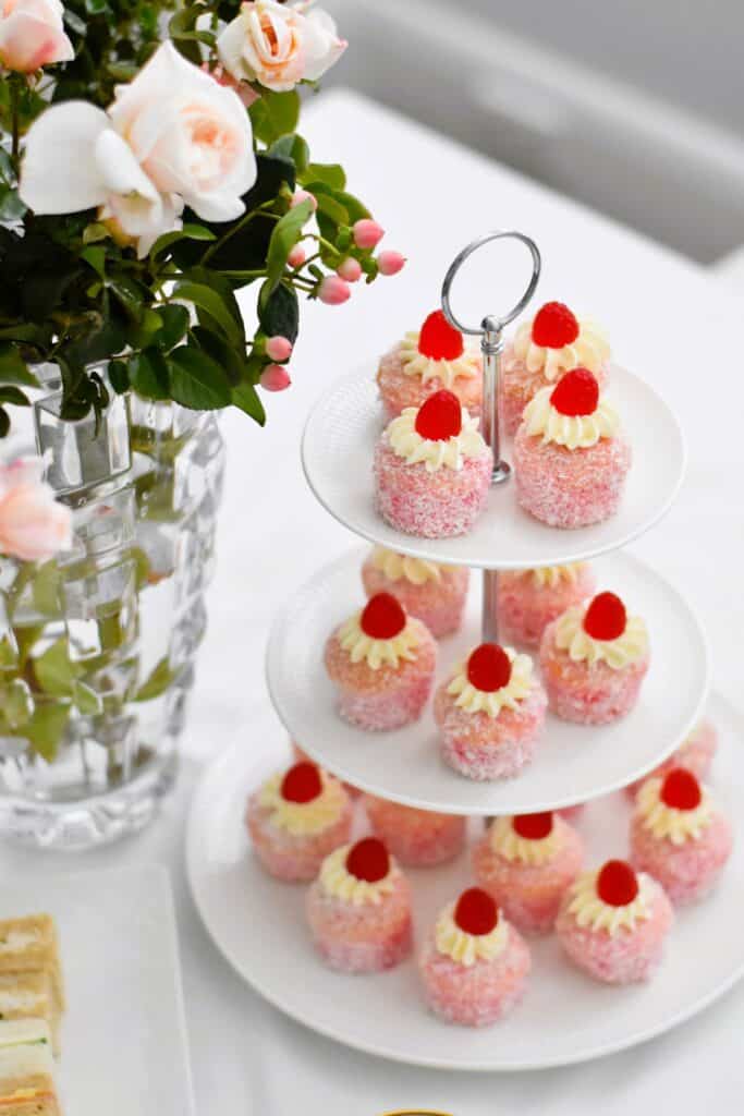 Little raspberry jelly cakes on a tiered stand with roses