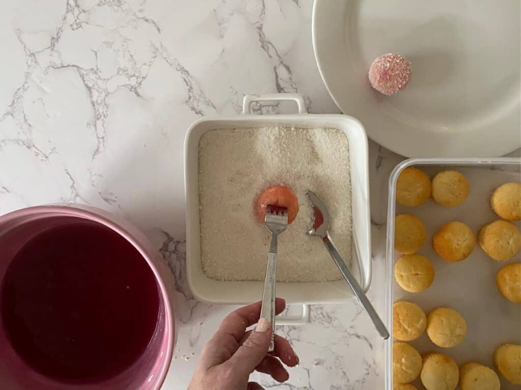 Coating the little raspberry jelly cakes in coconut