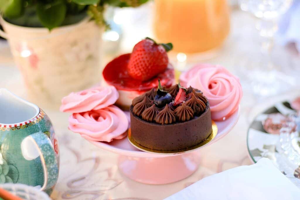 Hosting an afternoon tea little chocolate cakes and pink meringues
