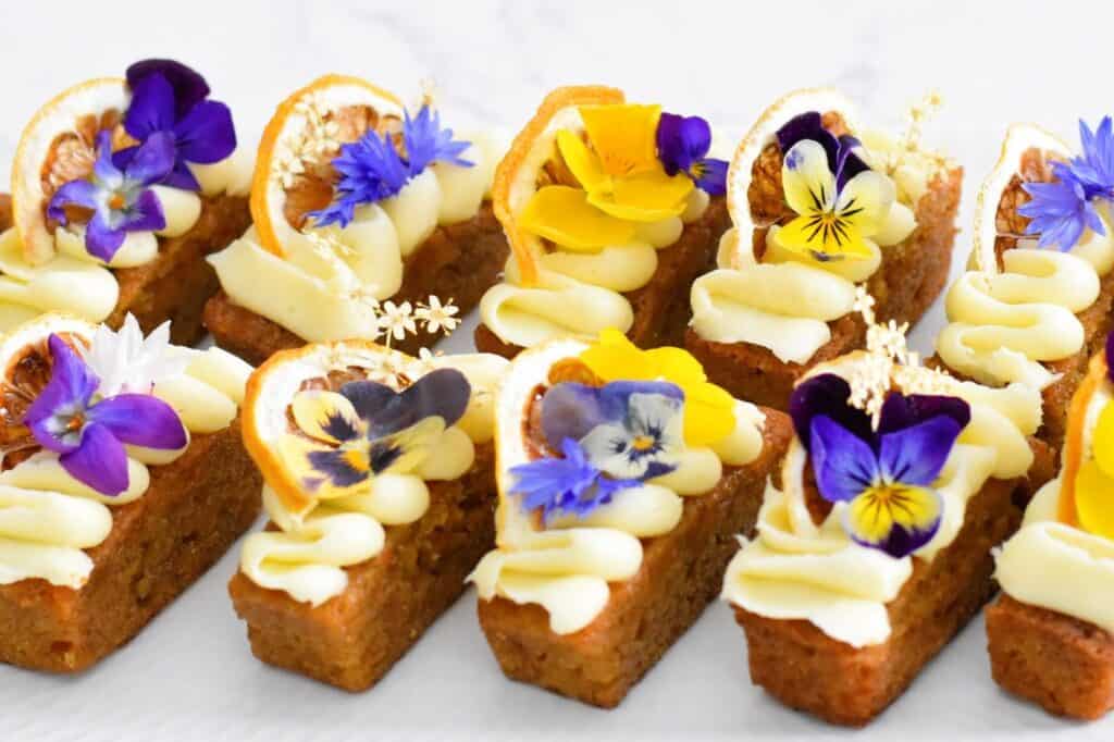 Carrot Cake Fingers with edible flowers on a platter