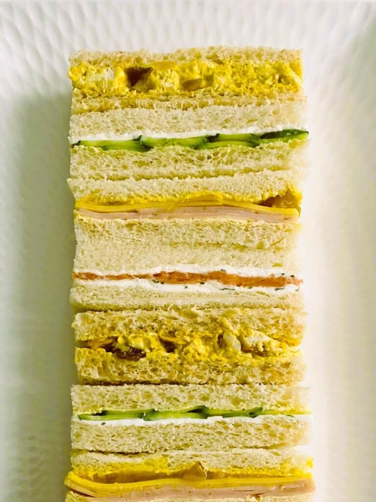Coronation chicken finger sandwiches with others on a platter