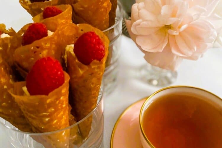 Brandy snap cones in glasses with a cup of tea