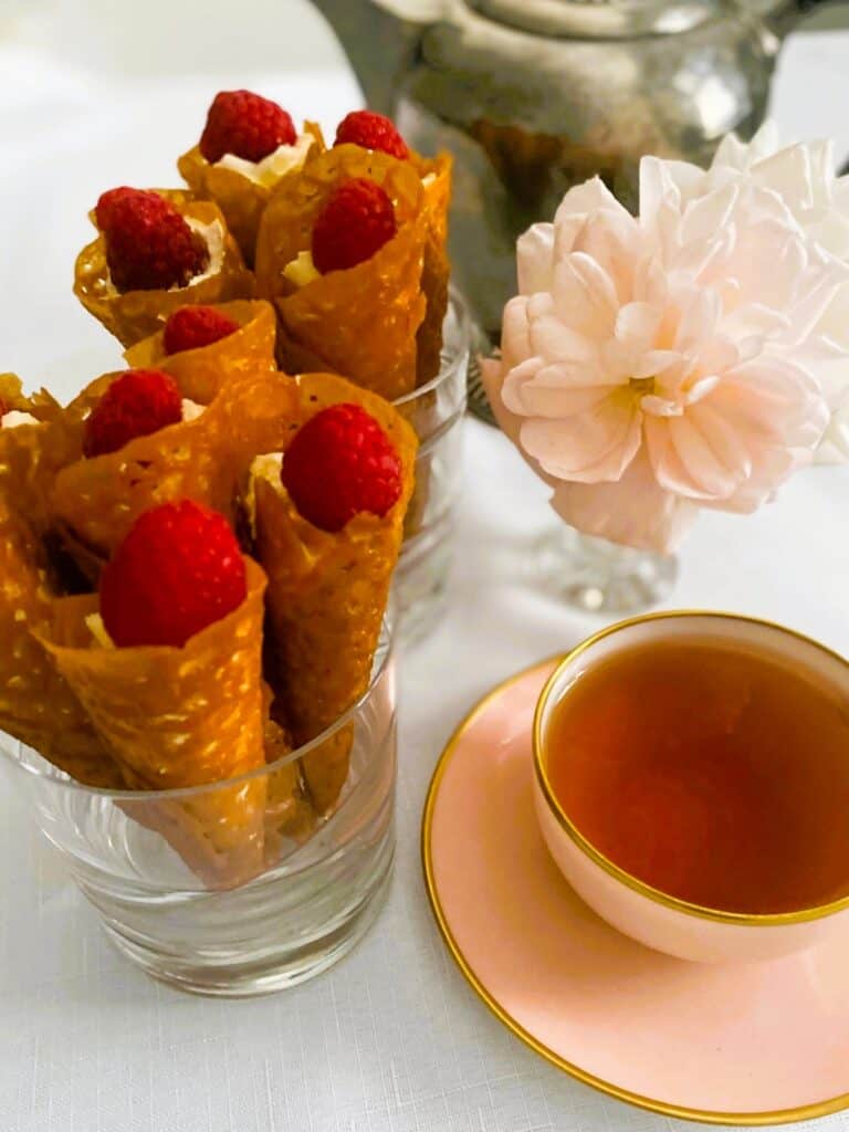 Brandy snap cones in glasses with a cup of tea