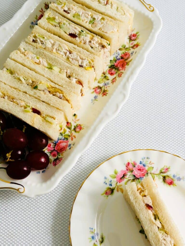 Chicken Waldorf finger sandwiches on a platter with one on a plate