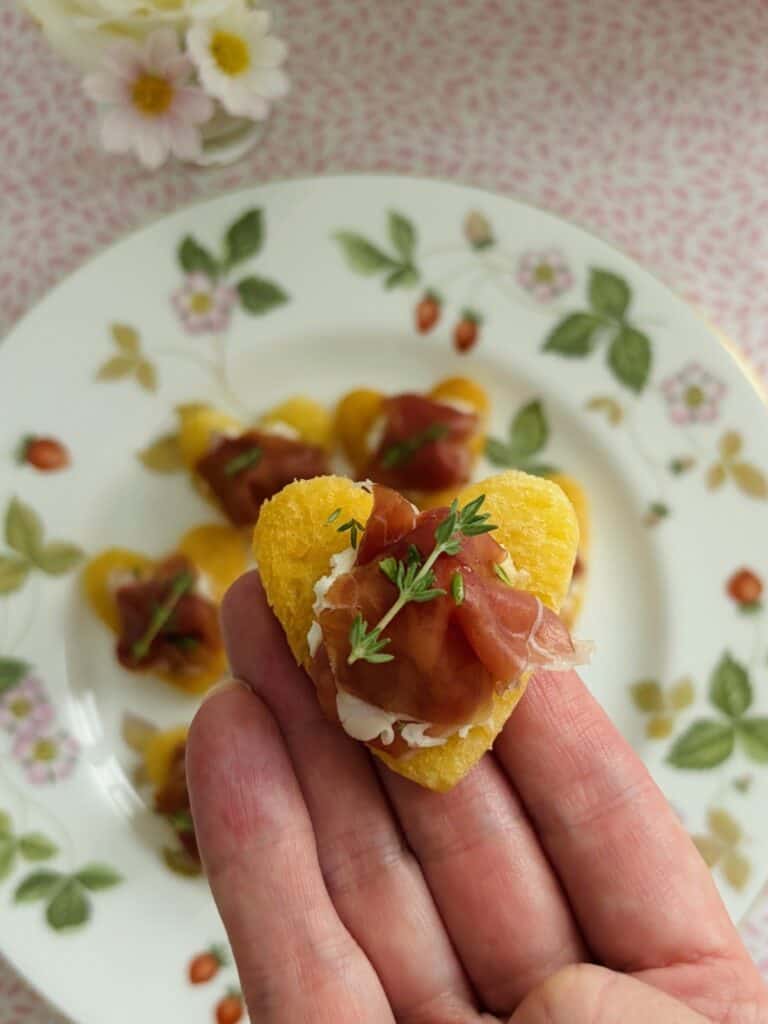 Prosciutto and goat's cheese heart in a hand