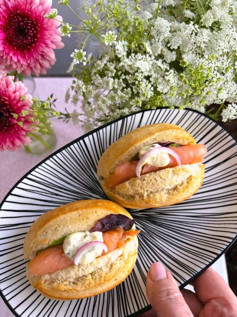 Two smoked salmon mini rolls on a black and white plate