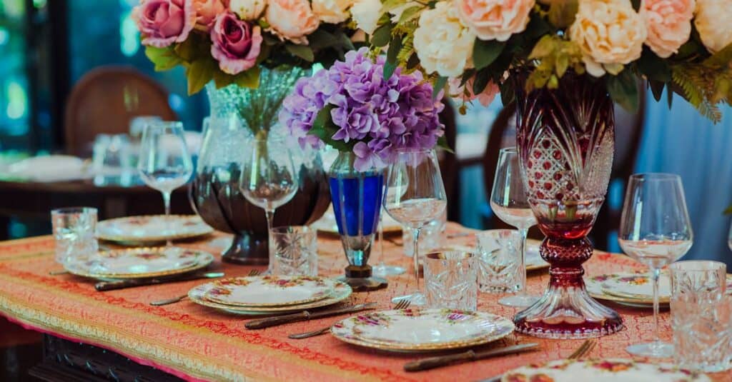 Elegant floral tablescape featuring vintage tableware, vibrant flower arrangements, and crystal glassware.