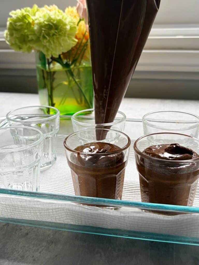 Piping chocolate mousse mixture into small glasses