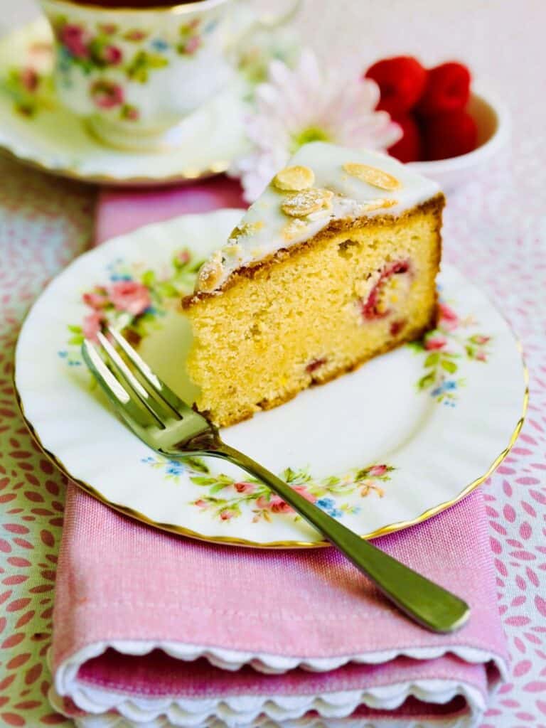 A slice of raspberry, lemon and almond cake on a plate with a fork