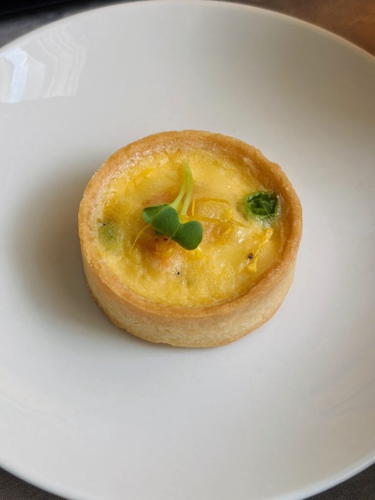 Individual salmon, pea and parmesan tartlet on a plate