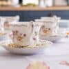 Delicate floral china cups elegantly set up for a tea party. Perfect for showcasing vintage charm.