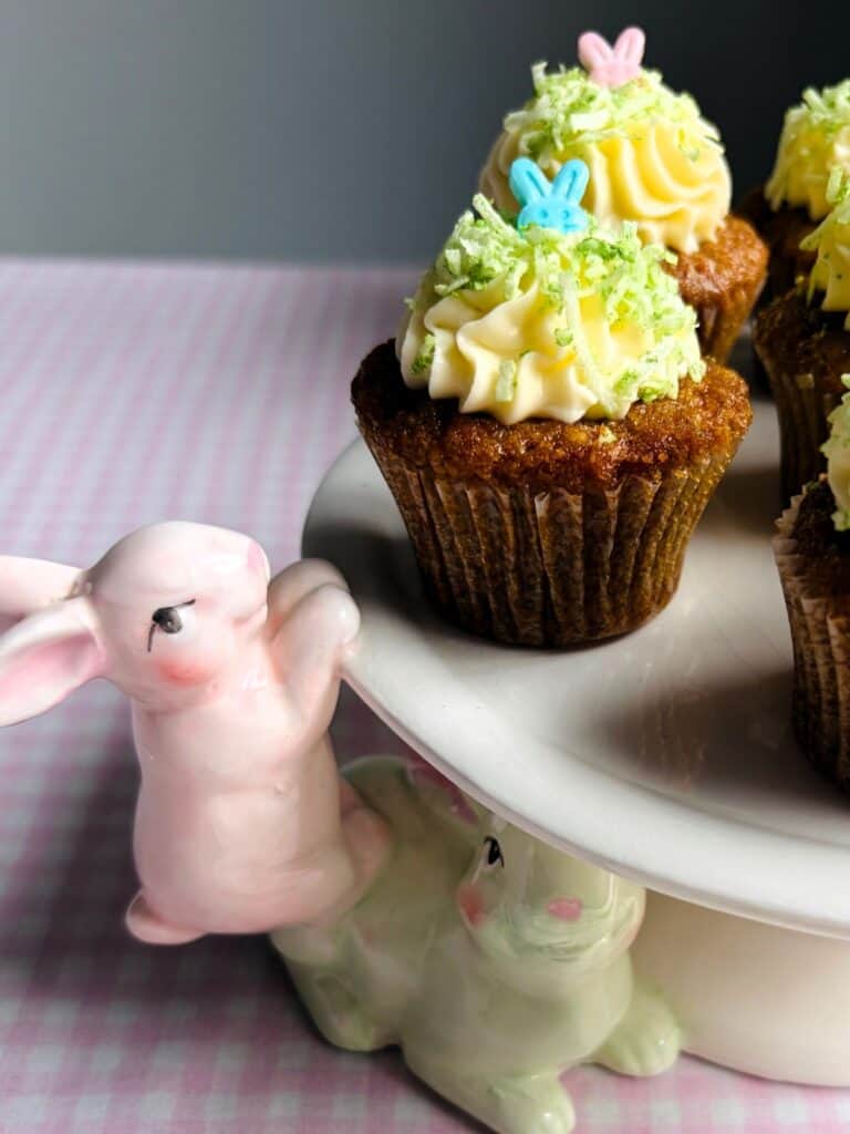 Easter-themed mini carrot cupcakes on an Easter bunny cake stand