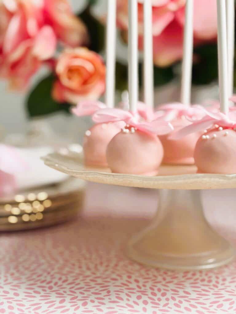 Raspberry and coconut truffle pops on a cake stand with roses