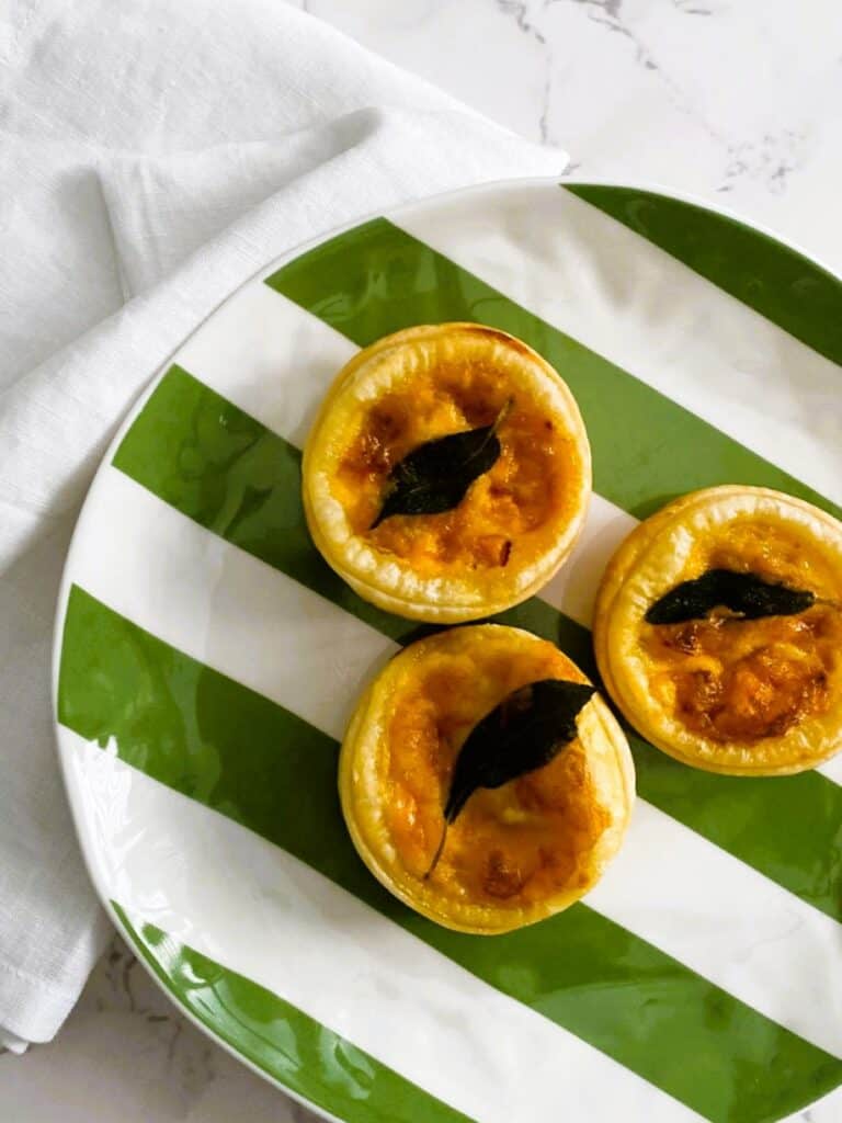 Pumpkin and sage mini quiche on a green and white striped plate