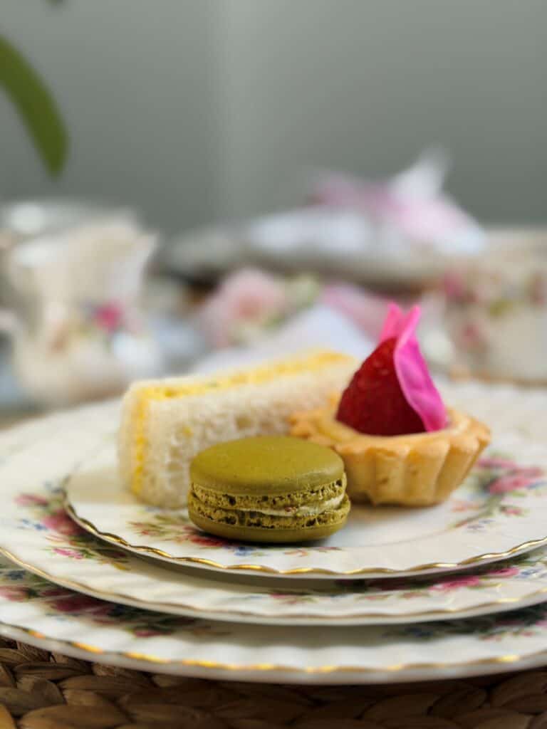 Little strawberry rose tartlets on a plate with a finger sandwich and pistachio macaron